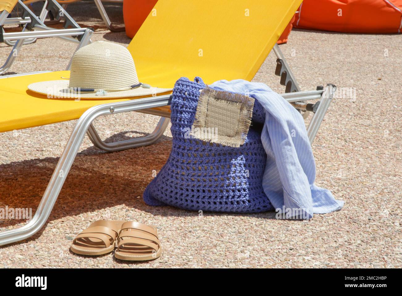 Sedia a sdraio e accessori estivi, borsa a uncinetto, cappello in paglia e ciabatte in pelle a bordo piscina Foto Stock