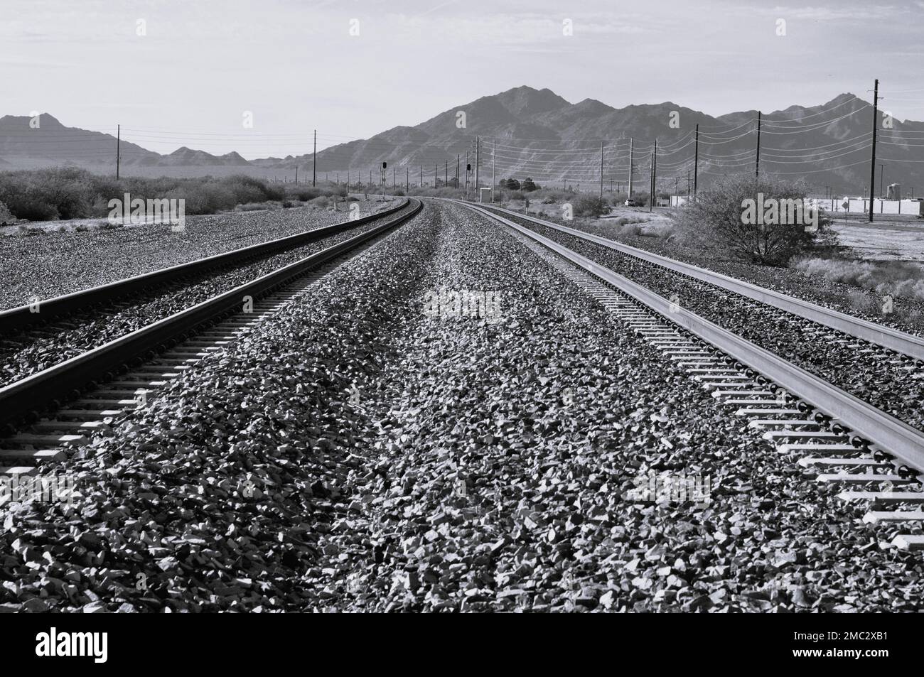 Un bel colpo in bianco e nero di ferrovie e strade di terra vicino alle alte montagne Foto Stock