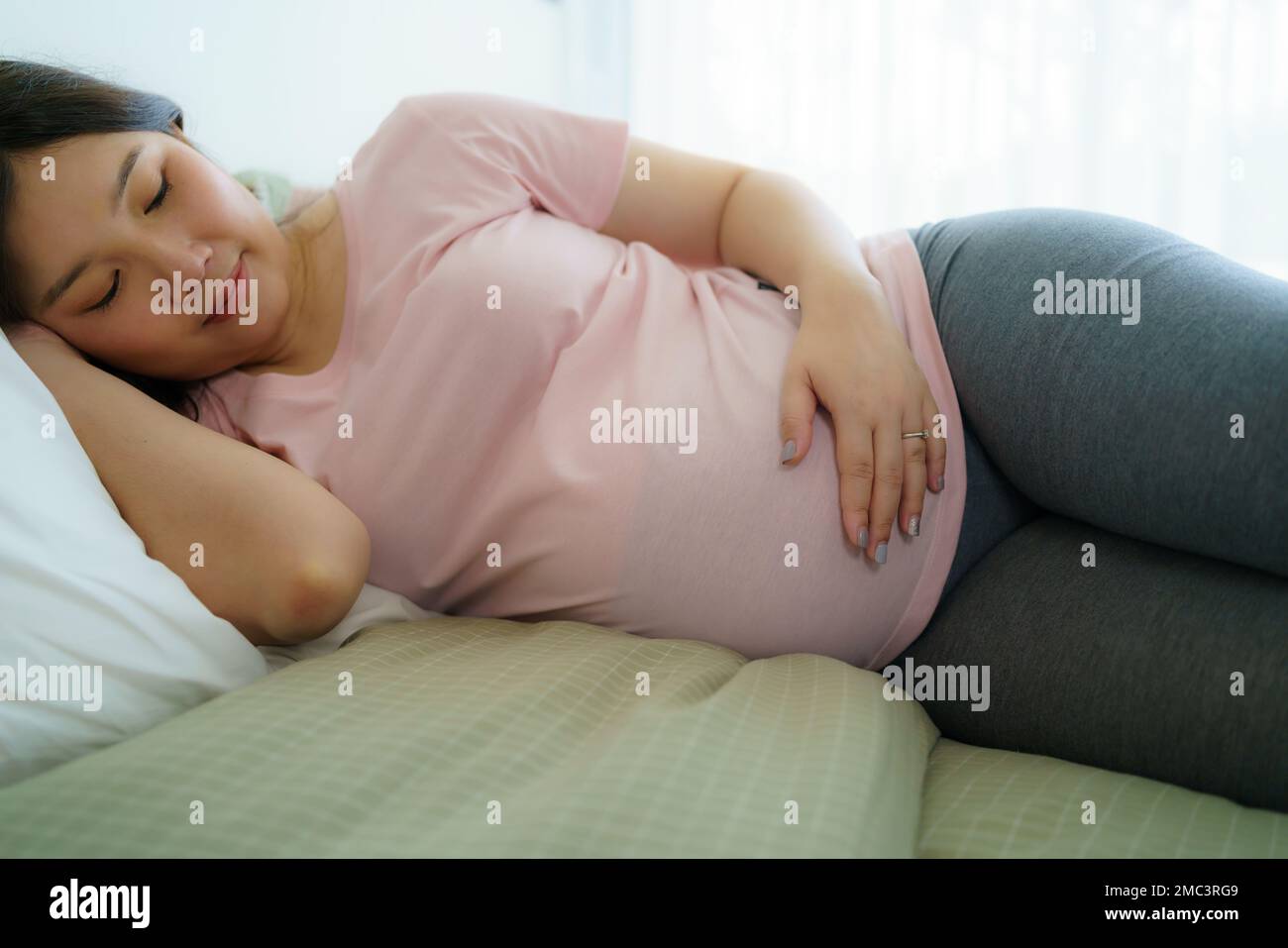 Gravidanza, riposo della gente e concetto di aspettativa - primo piano di sorridente donna incinta felice sdraiata a letto e toccando il suo ventre a casa. Foto Stock