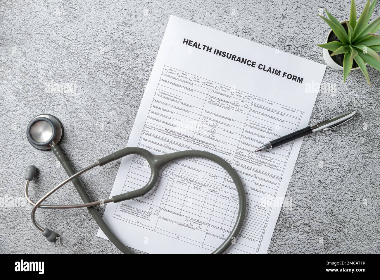 Vista dall'alto dello stetoscopio medico, penna e modulo di reclamo di assicurazione sanitaria sulla tabella Foto Stock