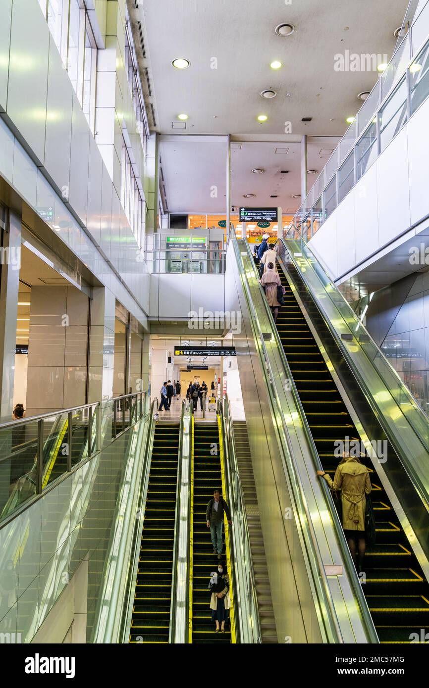 Tokyo Haneda airport terminal uno interno. Scale mobili che serve il piano terra al piano uno piano e uno al piano due con le persone che li utilizzano. Foto Stock