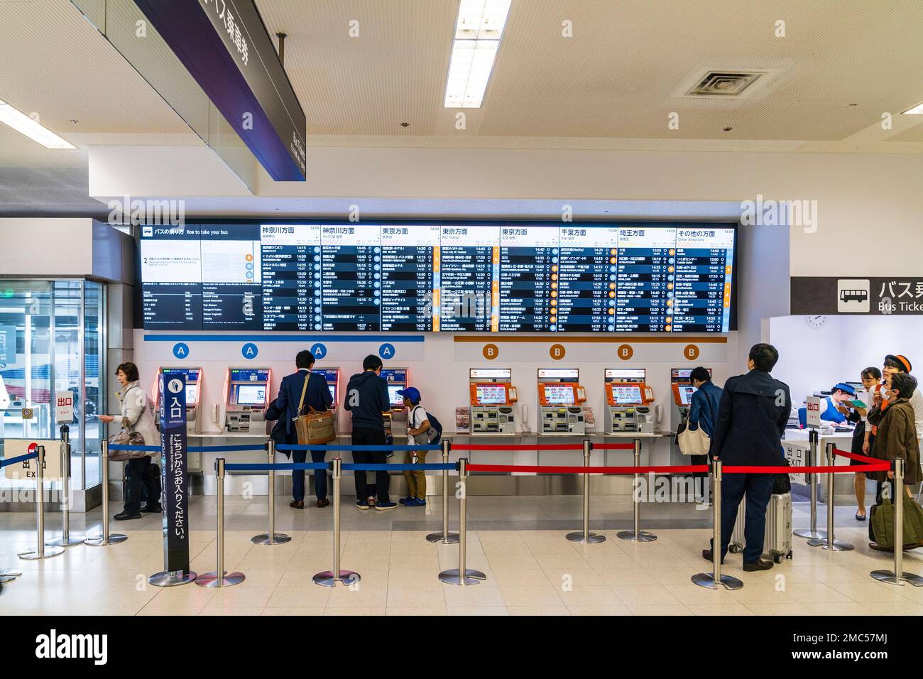 Tokyo Haneda international airport. Un terminale interno. Le persone che usano una fila di bus ticket macchine contrassegnate A e B, con calendario illuminata sopra. Foto Stock
