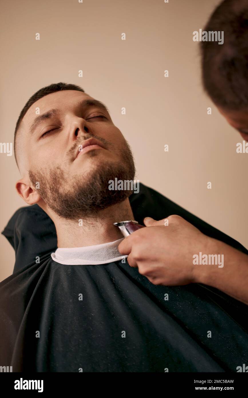 Barber rifinisci i capelli con il regolacapelli sul bel barbiere. Foto Stock