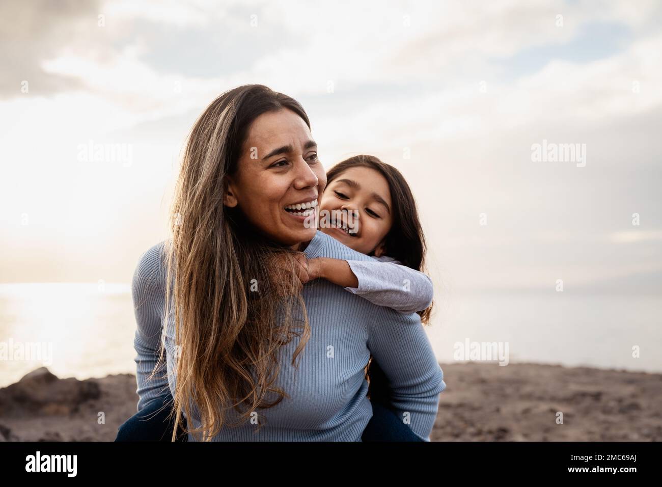 Felice madre latina godendo il tempo con il suo bambino sulla spiaggia - concetto di famiglia e amore Foto Stock