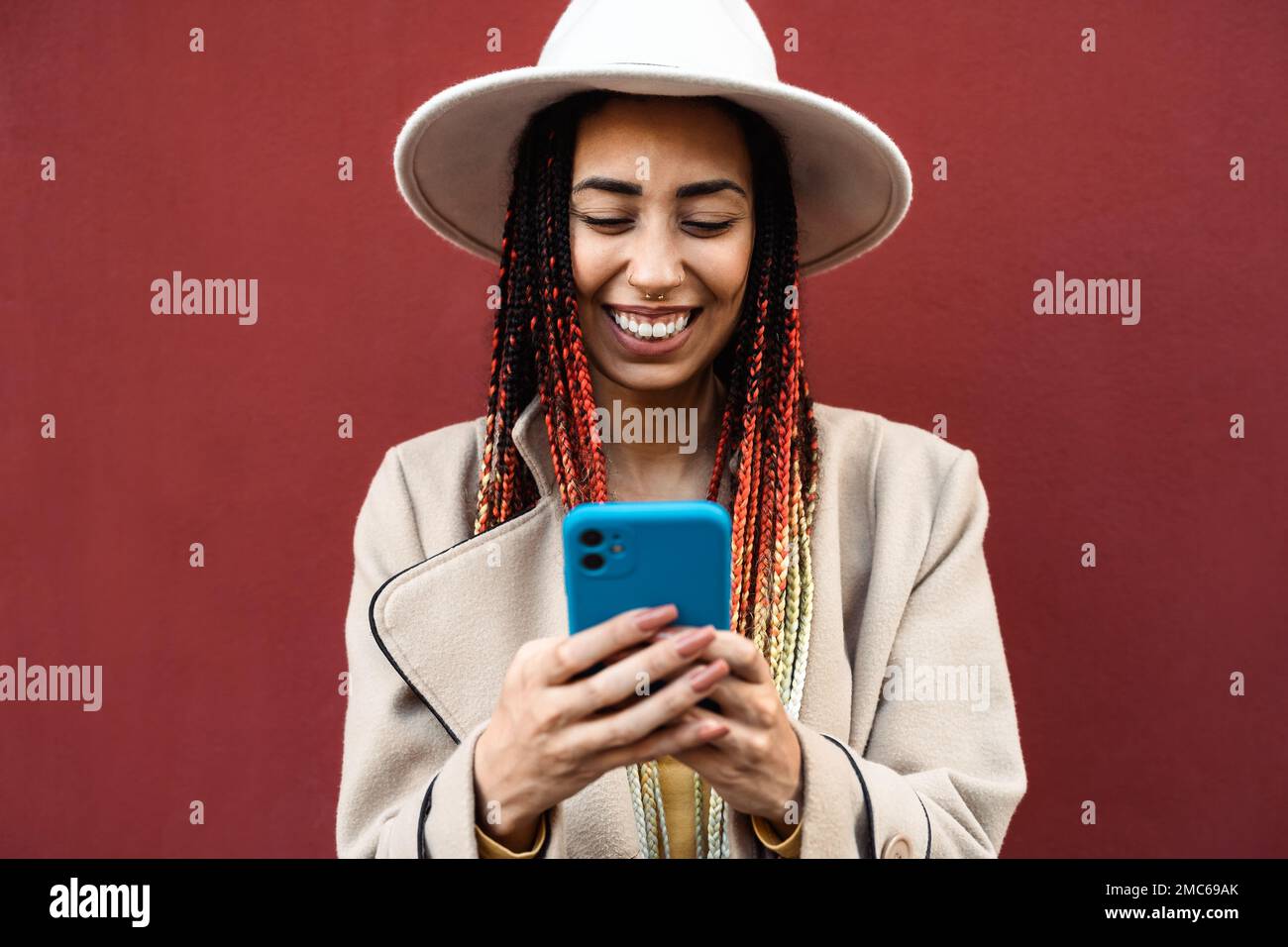 Felice giovane ragazza africana che si diverte utilizzando smartphone mobile all'aperto Foto Stock