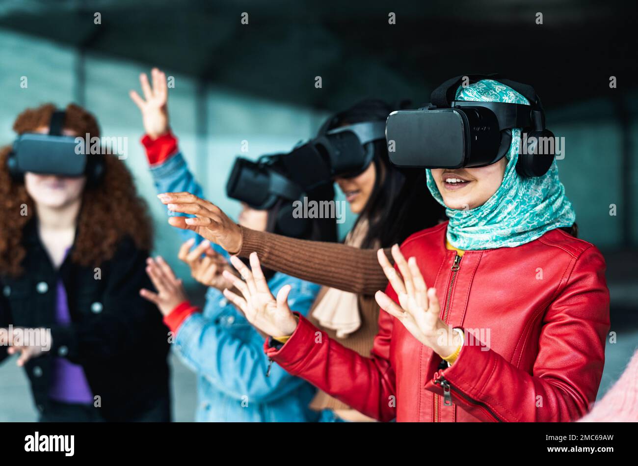 Giovani ragazze multirazziali che utilizzano occhiali futuristici per la realtà virtuale - tecnologia e concetto di metaverse Foto Stock