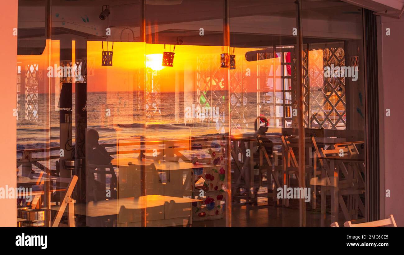 Paesaggio marino - vista del caffè costiero con il riflesso in vetro di alba sul mare, città di Varna, sulla costa del Mar Nero della Bulgaria Foto Stock