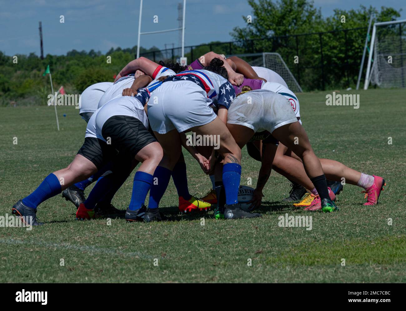 I membri della squadra di rugby femminile del Dipartimento dell'aeronautica  formano una mischia, dove i giocatori si legano e si sfidano per recuperare  la palla, durante una partita contro la squadra di