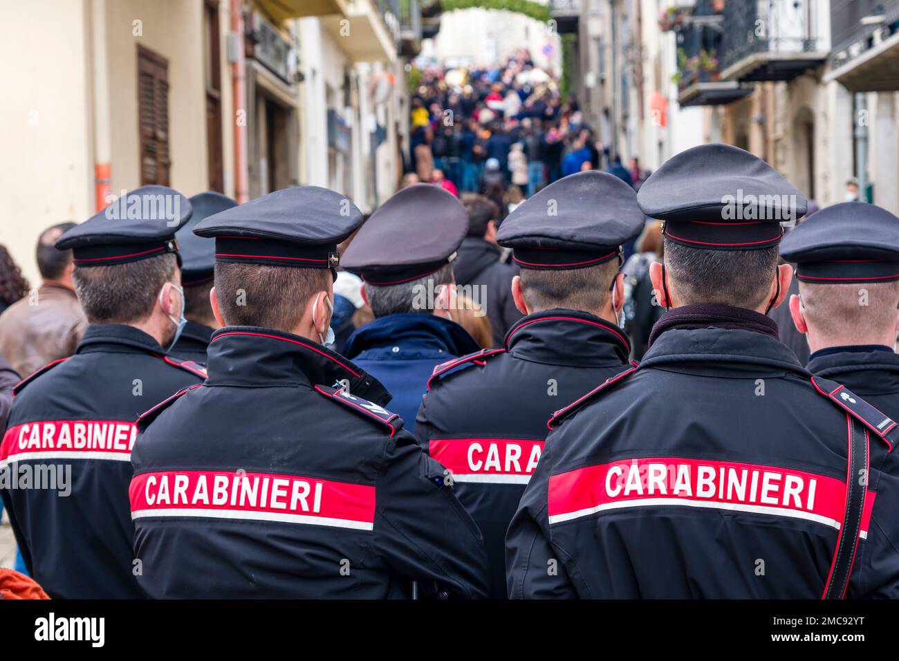 Un gruppo di poliziotti, carabinieri, osservano la processione pasquale nella cittadina di Prizzi. Foto Stock