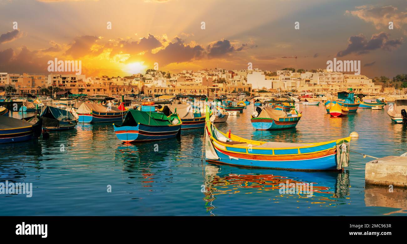 Vista del famoso villaggio di Marxassook e delle barche tradizionali sul porto di Malta, illuminato al tramonto, in Europa Foto Stock