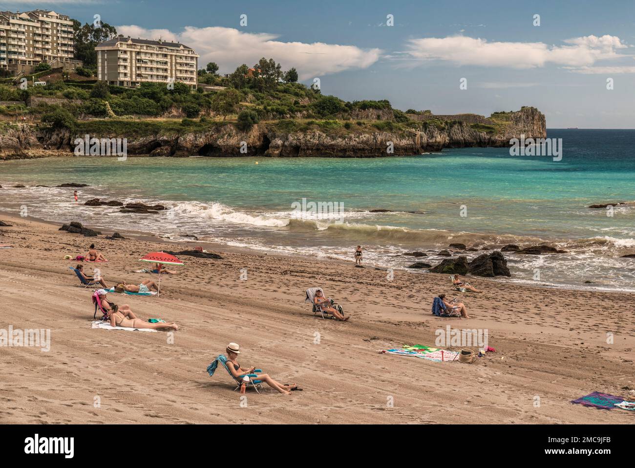 I turisti prendono il sole sulla sabbia della spiaggia di Ostende nella città di Castro Urdiales in provincia di Cantabria, Spagna, Europa Foto Stock