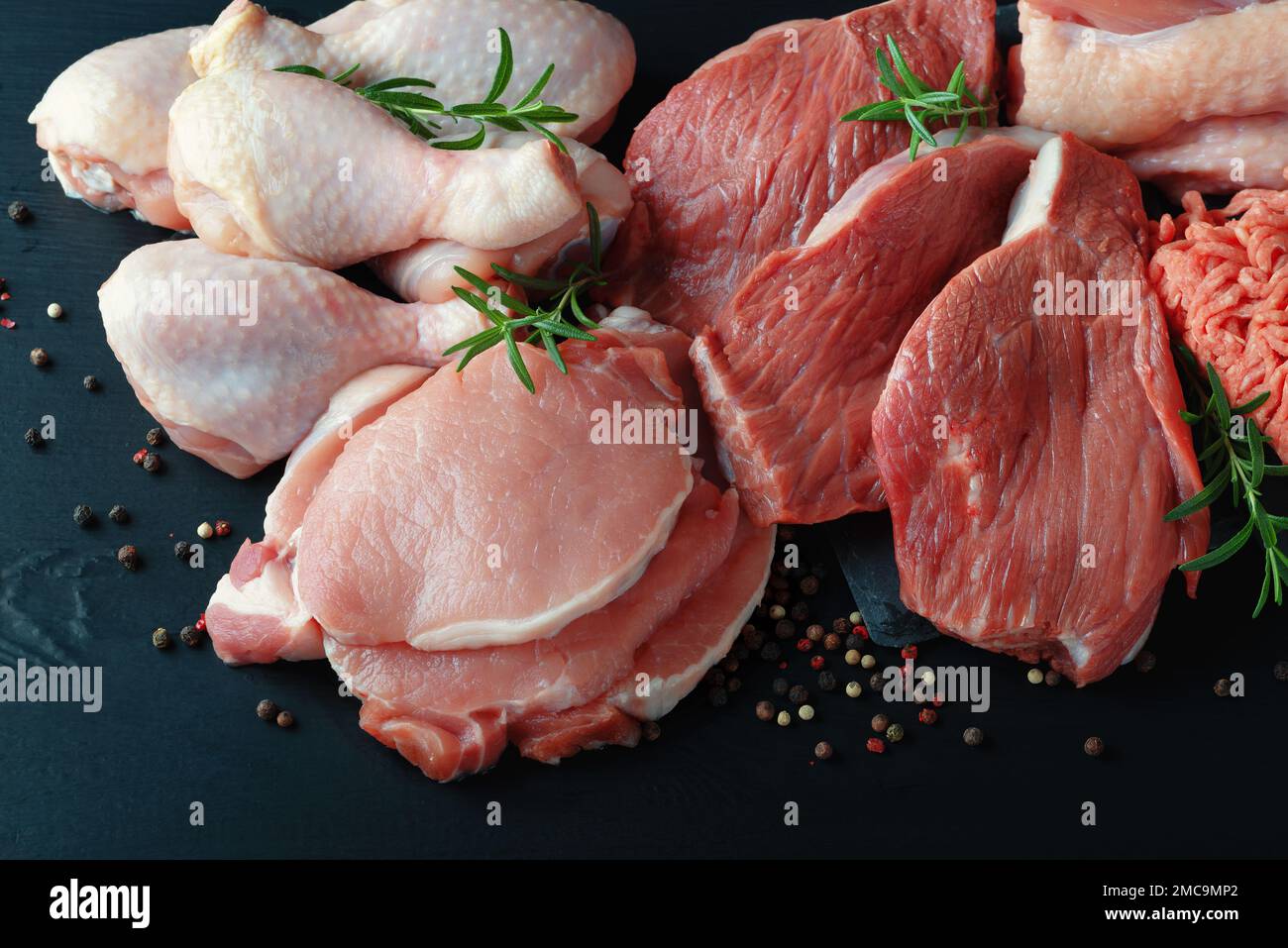 Vari tipi di carne fresca: Maiale, manzo, tacchino e pollo su un tavolo  nero di legno Foto stock - Alamy