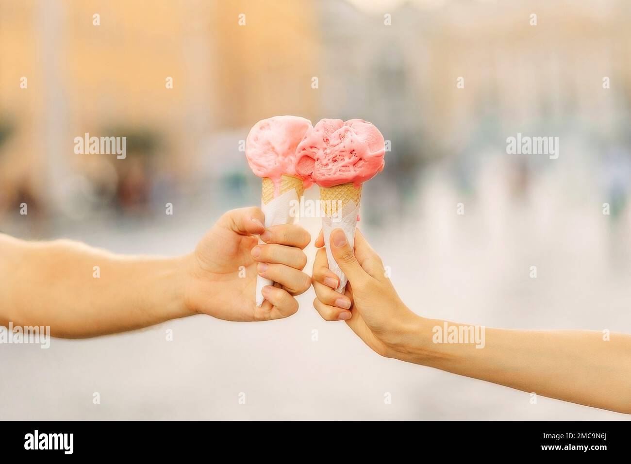Le mani da uomo e da donna tengono un cono gelato luminoso. Mani che tengono il cono gelato. Estate. Intrattenimento turistico Foto Stock