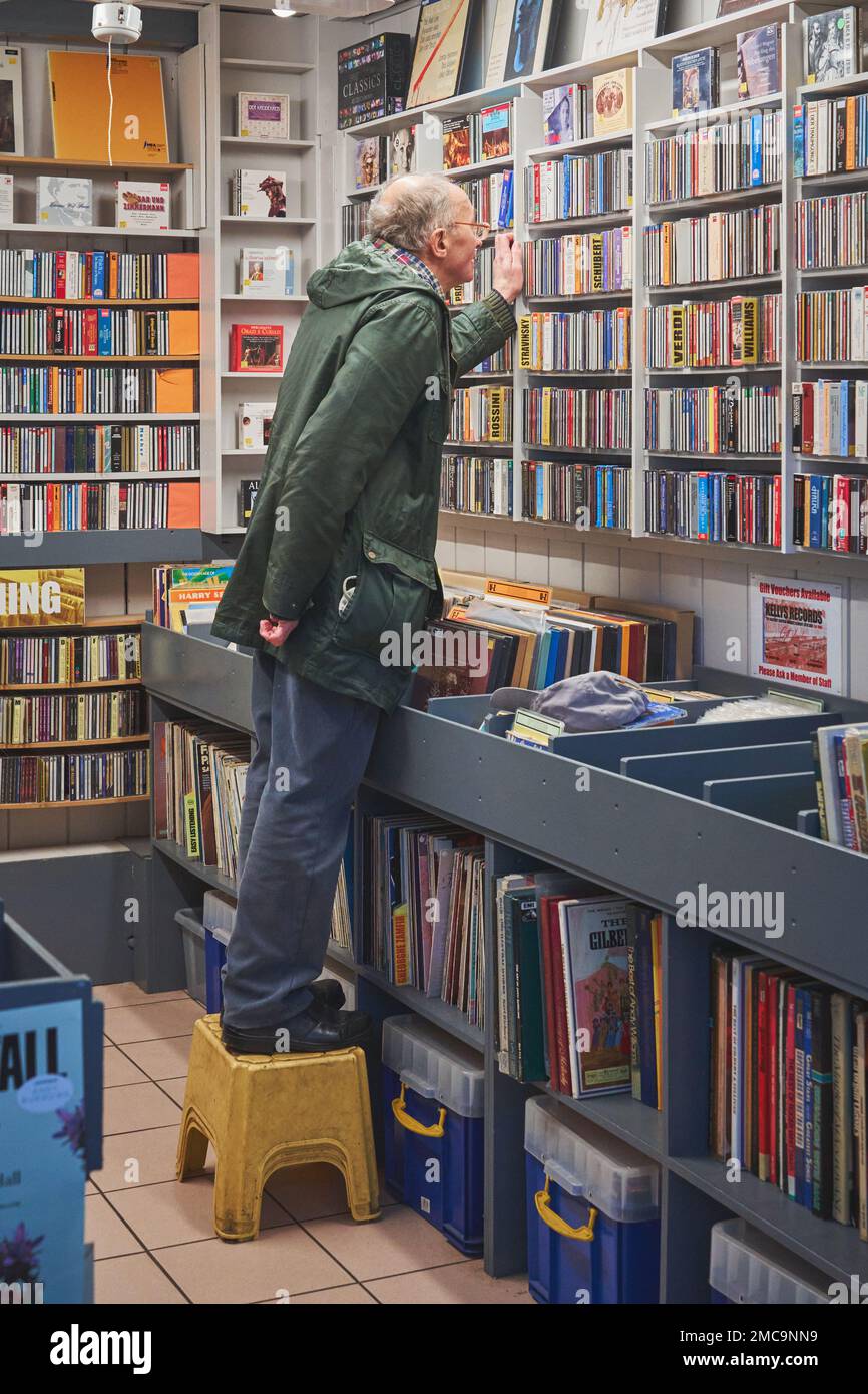 Un acquirente che esplora i CD di seconda mano nel mercato indoor di Cardiff, Cardiff, Galles del Sud Foto Stock