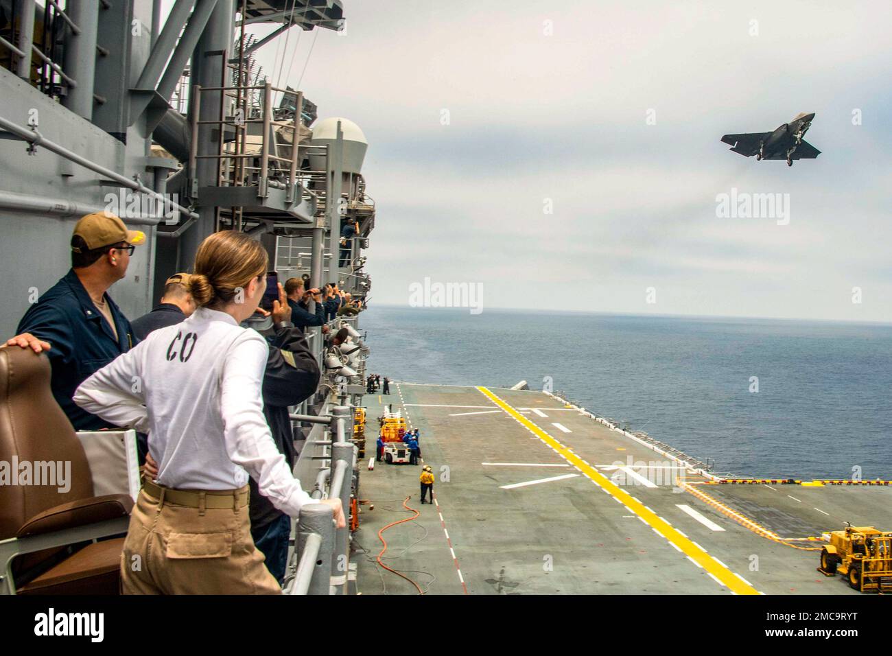 Kathleen Ellis, comandante della nave d'assalto anfibio USS Boxer (LHD 4) e nativo di Westford, Connecticut, (27 giugno 2022), Osserva un F-35C Marine Lightning II volare sopra la nave durante il suo primo corso in più di due anni dopo il completamento di una disponibilità di manutenzione programmata. Boxer è una nave d'assalto anfibio di classe Wasp ospita a San Diego. Foto Stock