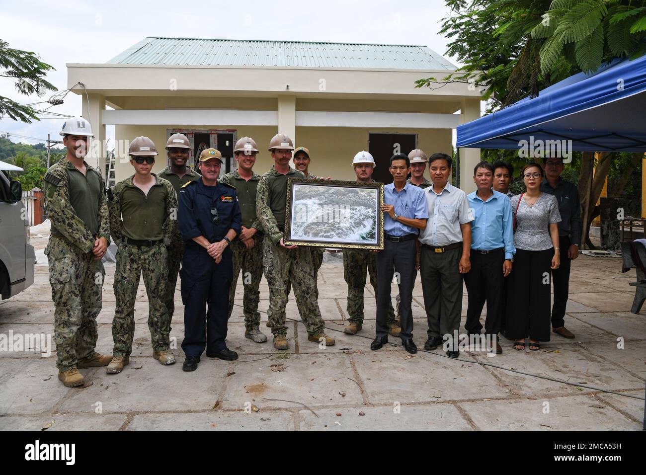 220628-N-NC885-1018 PHU YEN, VIETNAM (28 giugno 2022) – il capitano della Marina reale britannica Charles Maynard, il vice comandante della missione del Pacific Partnership 2022 (PP22), e i membri del Battaglione delle costruzioni anfibie 1 (ACB1) ricevono una foto incorniciata dalla direzione del distretto per contribuire a rinnovare la scuola di un Ninh Dong in Vietnam. Ora nel suo 17th° anno, Pacific Partnership è la più grande missione multinazionale annuale di assistenza umanitaria e di preparazione alle catastrofi condotta nell'Indo-Pacifico. Foto Stock