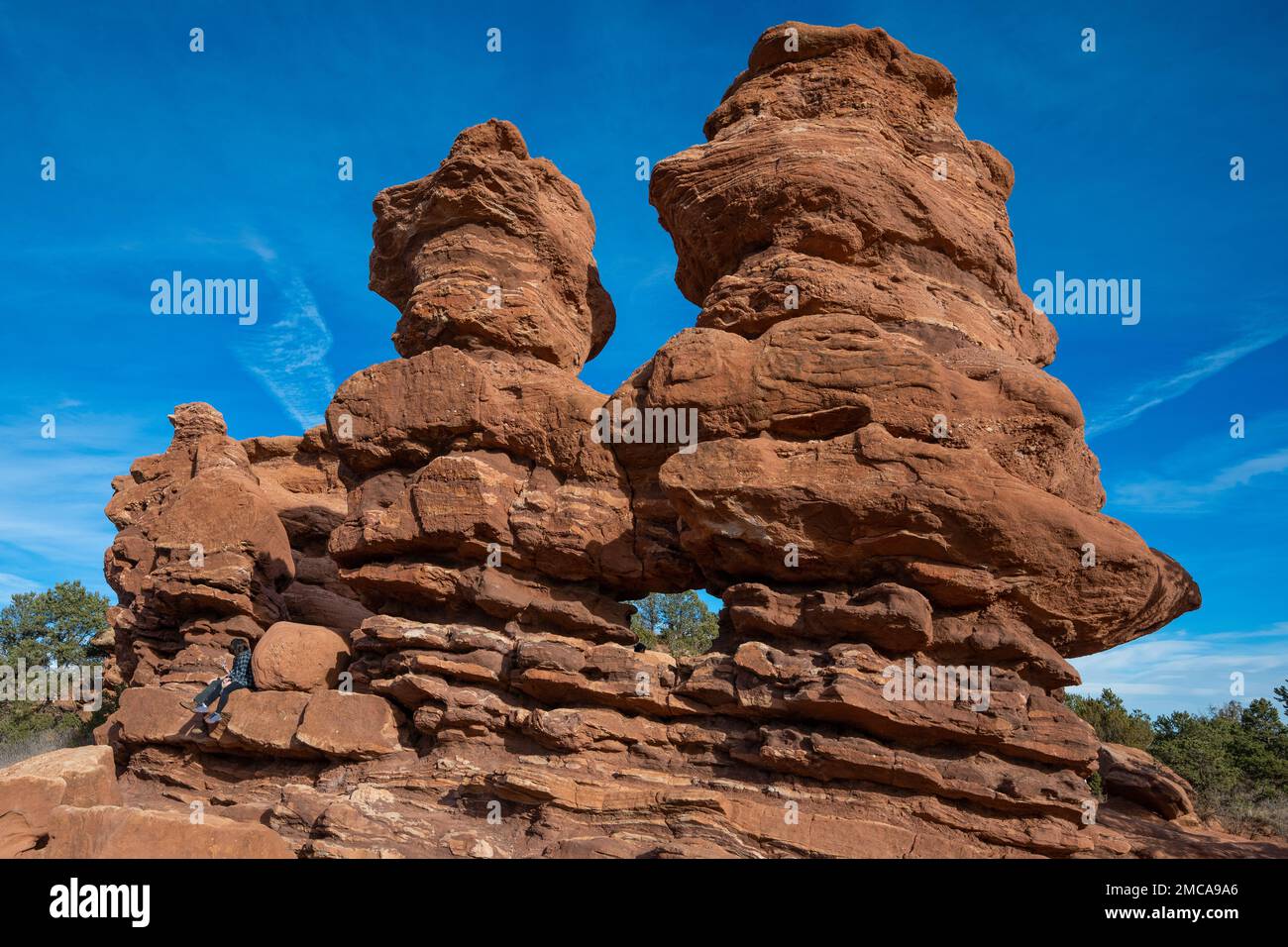 Due pinnacoli di pietra arenaria rossa con una finestra naturale erosa nel loro centro in una posizione naturale circondata da un bel cielo blu chiaro Foto Stock