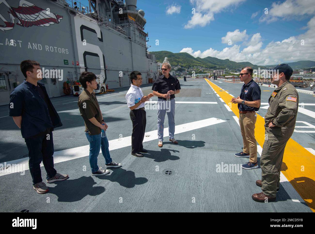 Hideo INAO, rappresentante del municipio di Yatsushiro, parla con John Taylor, funzionario principale degli Stati Uniti Consolato a Fukuoka, centro, Aki Nichols, funzionario per gli affari pubblici del comandante, Fleet Activities Sasebo (CFAS), Lt. Dave Perry, assegnato alla nave d'assalto anfibia USS America (LHA 6) e membri del Yatsushiro Student Volonteer Group (YSVG) durante un tour dell'America al CFAS del 29 giugno 2022. Taylor e la YSVG si sono incontrati alla CFAS come parte di una corrispondenza in corso tra la YSVG e il consolato che ha iniziato a seguito del supporto militare degli Stati Uniti per gli sforzi di soccorso della forza di autodifesa del Giappone Foto Stock