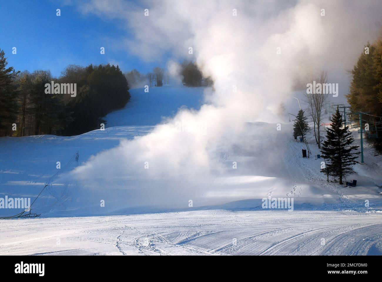 Le macchine per la neve spruzzano neve nuova sulle piste da sci di montagna in Vermont in inverno Foto Stock