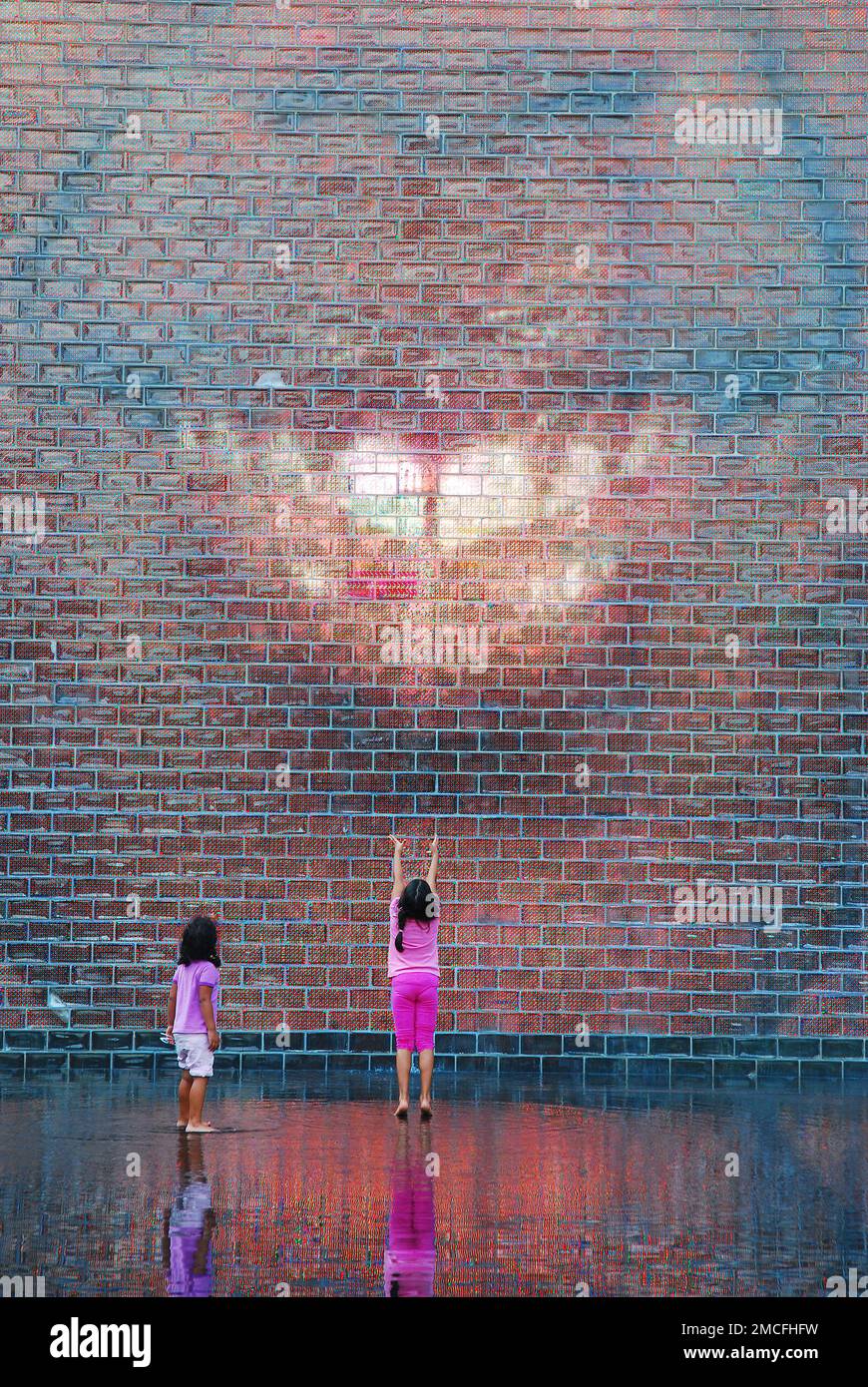 Due ragazze aspettano la Crown Fountain, una mostra d'arte che mostra immagini video di vari cittadini, per sgombrare l'acqua nel Millennium Park, Chicago Foto Stock