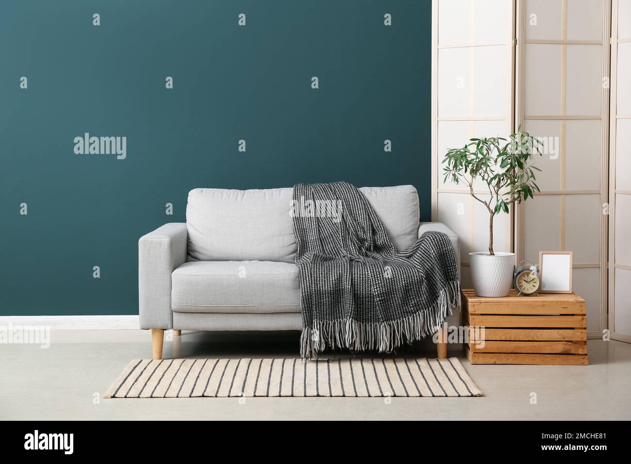 Interno di elegante soggiorno con divano grigio, scatola di legno e schermo  pieghevole Foto stock - Alamy