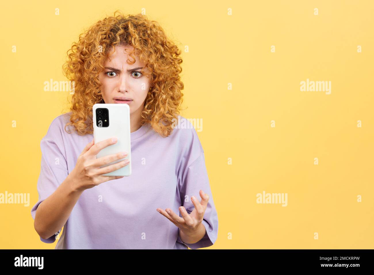 Donna preoccupata con capelli ricci usando un mobile Foto Stock