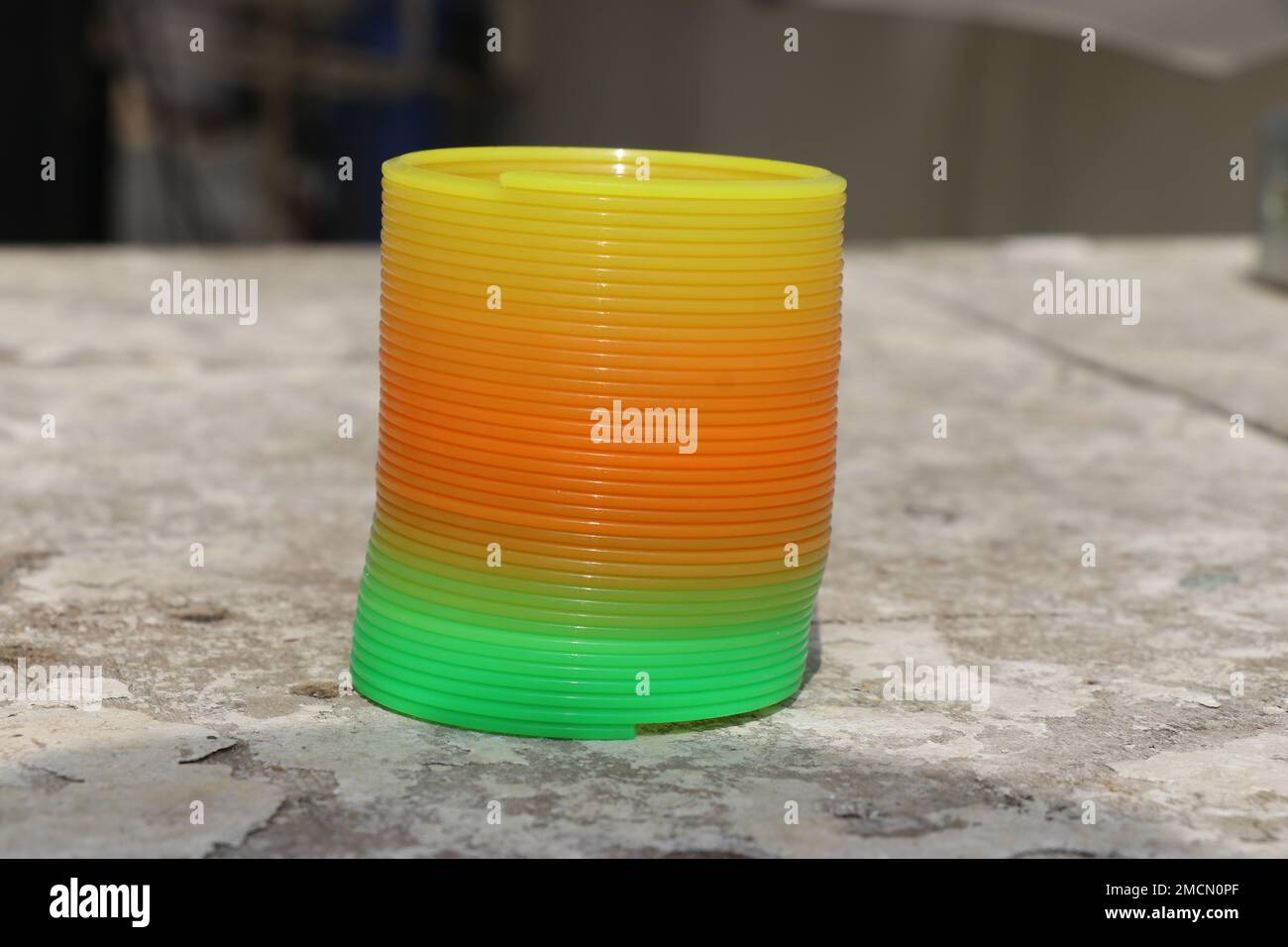 Colorato giocattolo a spirale arcobaleno tenuto su uno sfondo di legno. Sorgenti arcobaleno Foto Stock