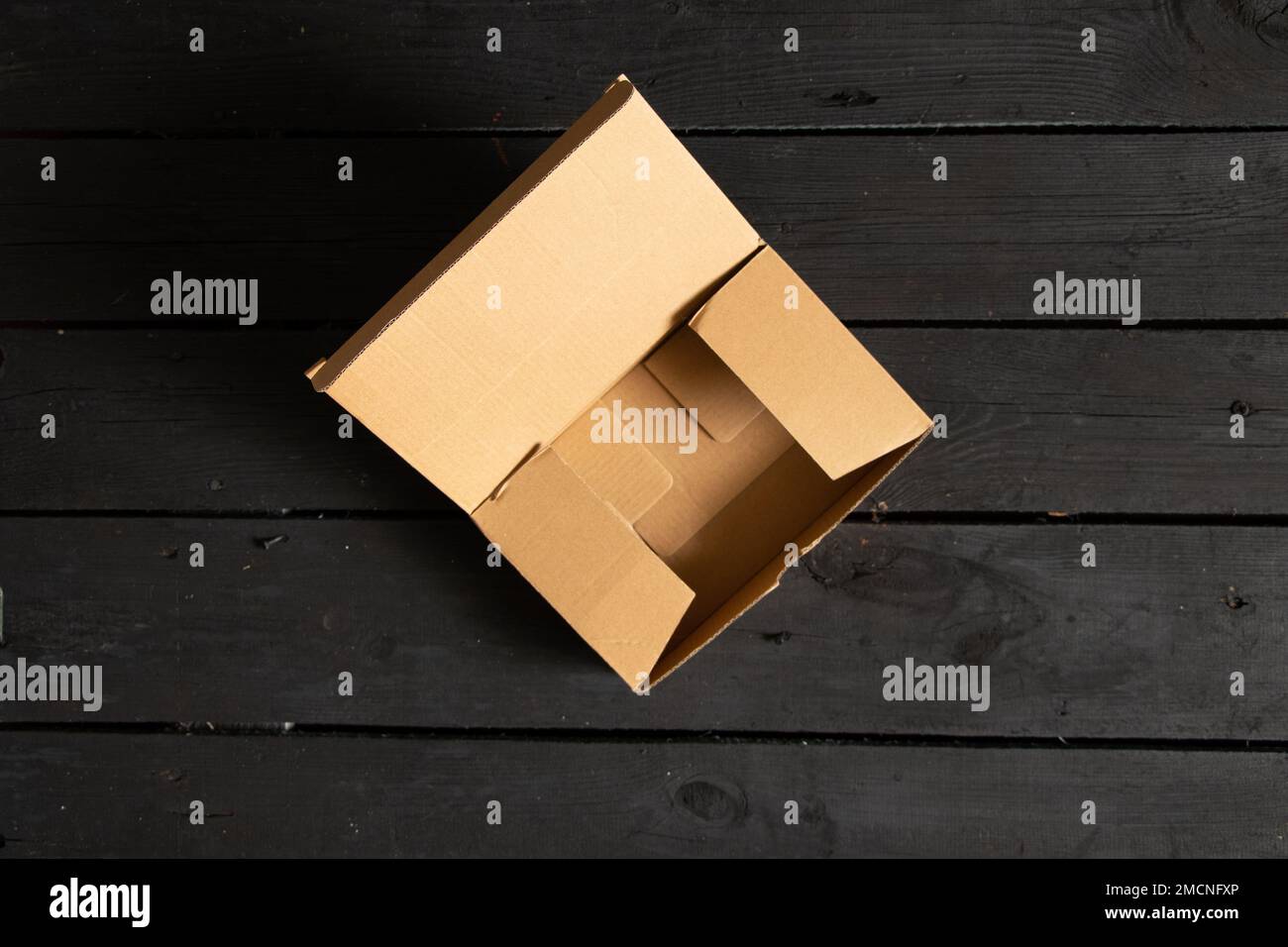 scatole aperte in cartone vuote su pavimento in legno nero, cassetta postale Foto Stock