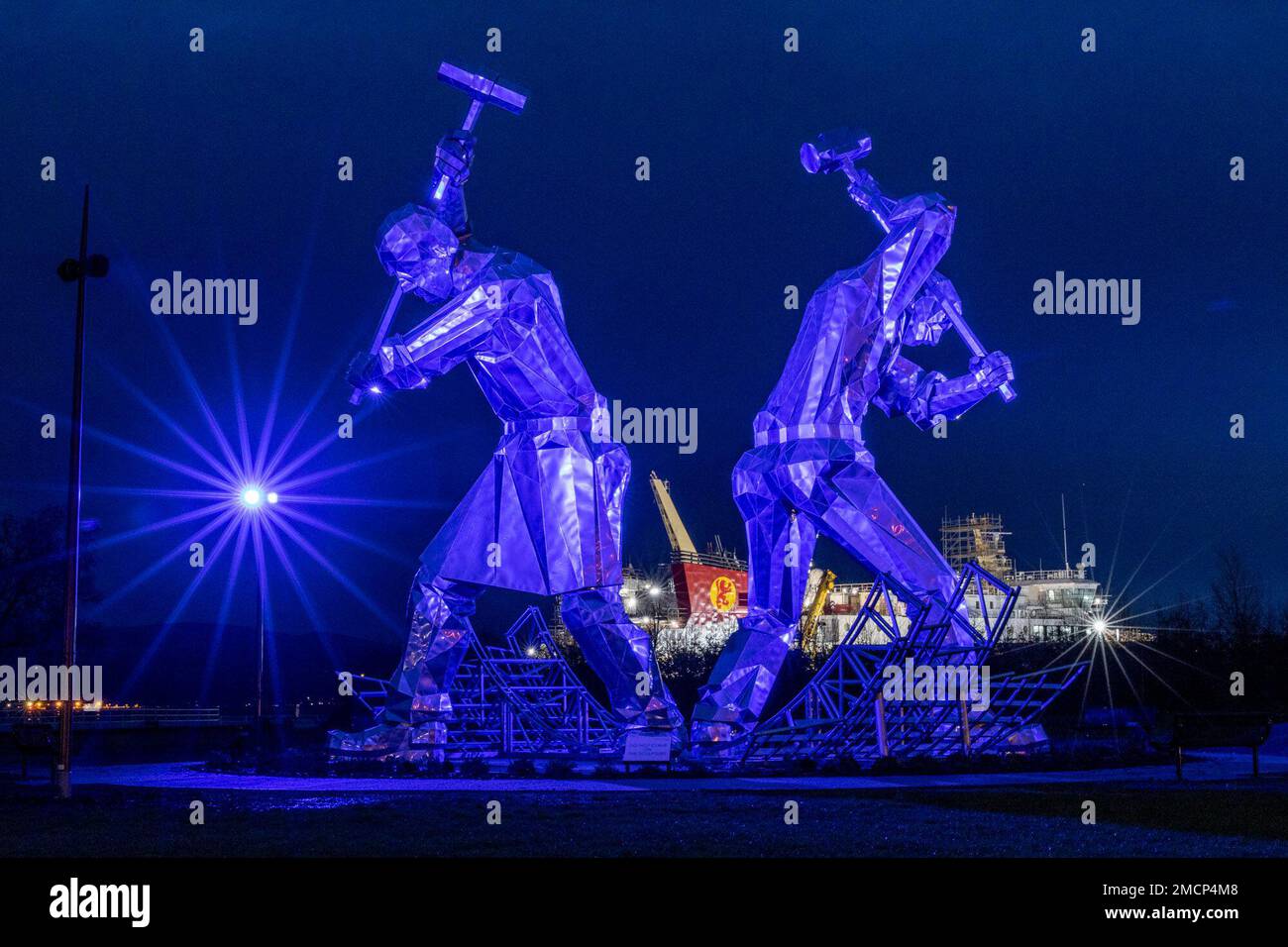 Greenock, Regno Unito. 21 gennaio 2023 nella foto: La scultura di Port Glasgow dei costruttori navali di John McKenna è illuminata di fronte al traghetto Glen Sannox in costruzione presso il cantiere navale Ferguson. Credit: Notizie dal vivo su Rich Dyson/Alamy Foto Stock