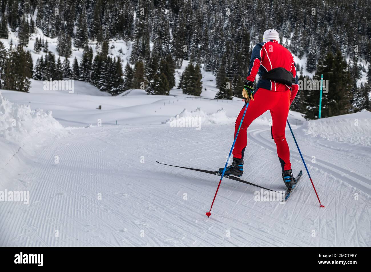 Man in Red Overall pattina da fondo sulle piste da fondo in Svizzera Foto Stock