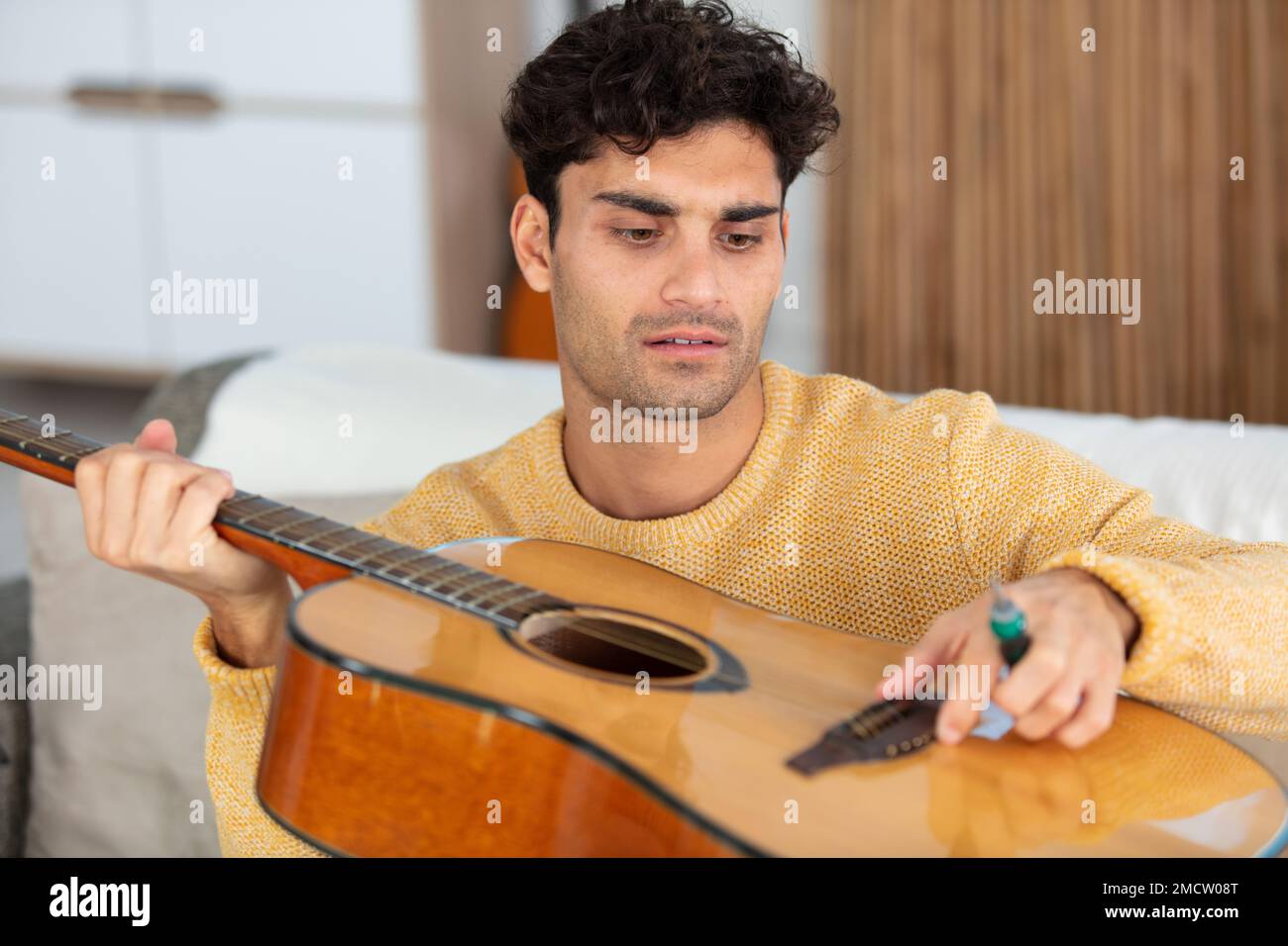 bell'uomo che ripara una chitarra acustica Foto Stock