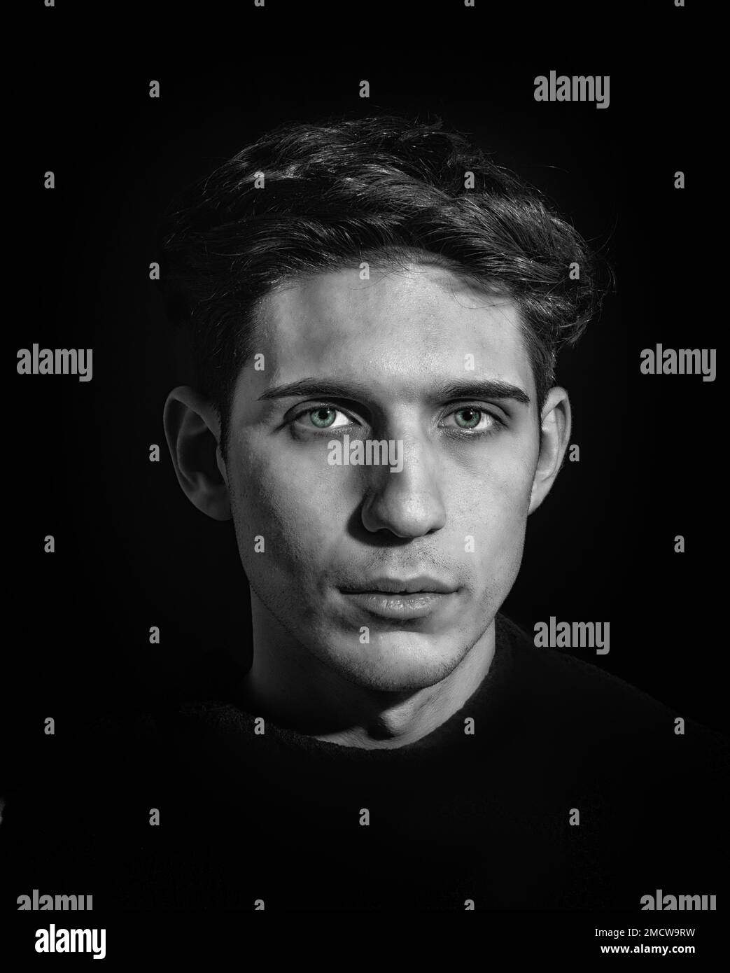 Primo piano di un giovane uomo, capelli scuri e occhi verdi Foto Stock