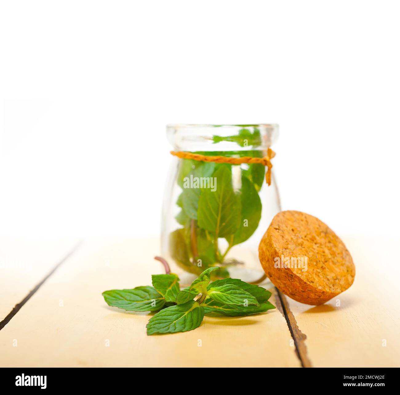 Foglie di menta fresca su una vetrata di un rustico tavolo di legno bianco Foto Stock