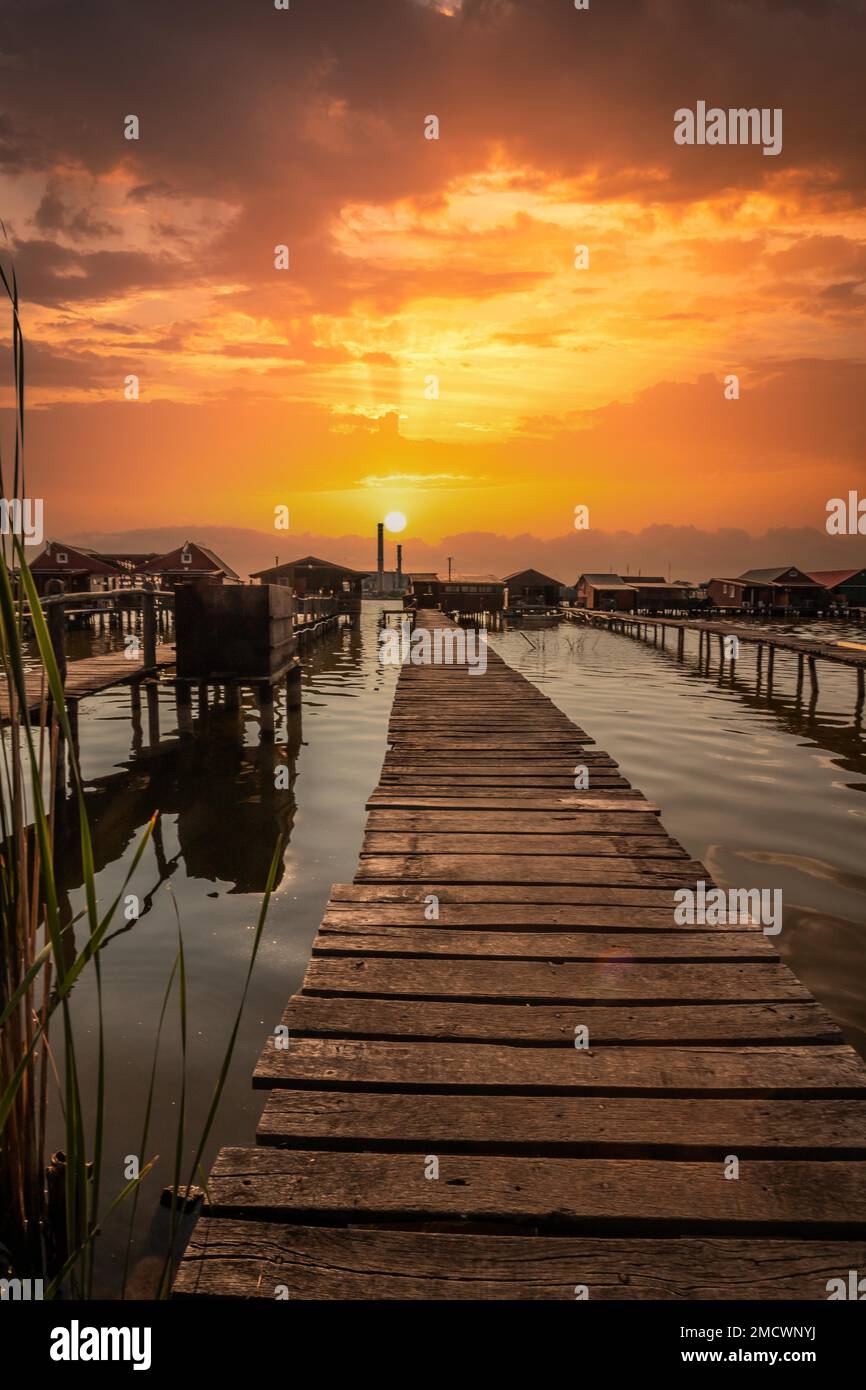 Piccole case di legno con un molo in un lago, servono come case di pesca e vacanze per gli ungheresi. Bellissima foto di paesaggio al tramonto, Lago Bokodi Foto Stock