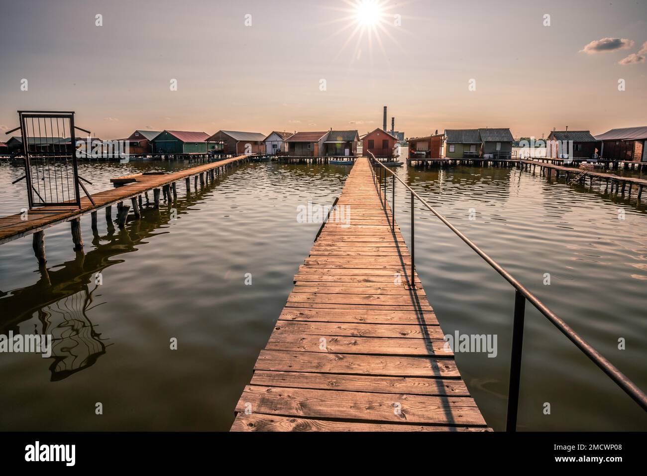 Piccole case di legno con un molo in un lago, servono come case di pesca e vacanze per gli ungheresi. Bellissima foto di paesaggio al tramonto, Lago Bokodi Foto Stock