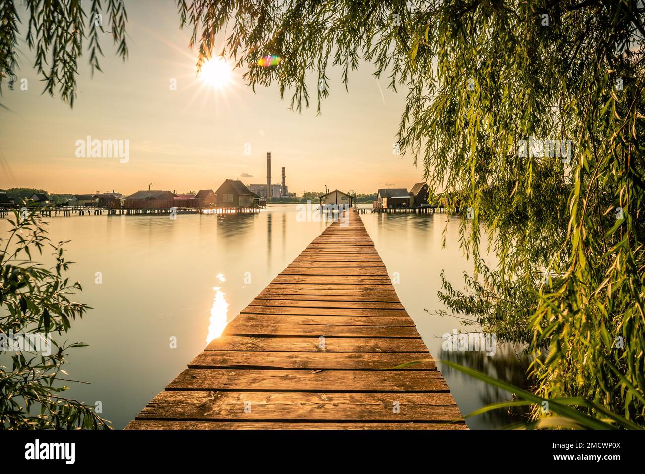 Piccole case di legno con un molo in un lago, servono come case di pesca e vacanze per gli ungheresi. Bellissima foto di paesaggio al tramonto, Lago Bokodi Foto Stock