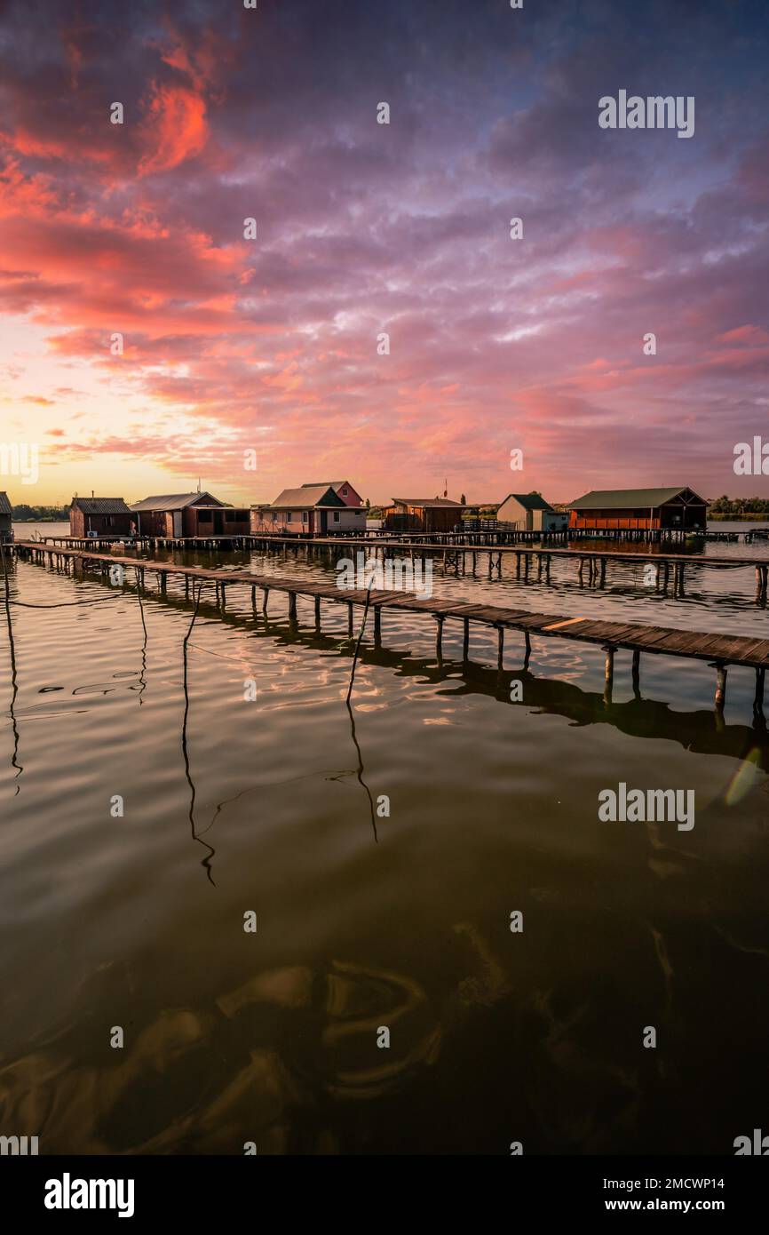 Piccole case di legno con un molo in un lago, servono come case di pesca e vacanze per gli ungheresi. Bellissima foto di paesaggio al tramonto, Lago Bokodi Foto Stock