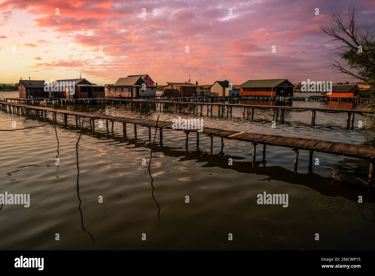 Piccole case di legno con un molo in un lago, servono come case di pesca e vacanze per gli ungheresi. Bellissima foto di paesaggio al tramonto, Lago Bokodi Foto Stock