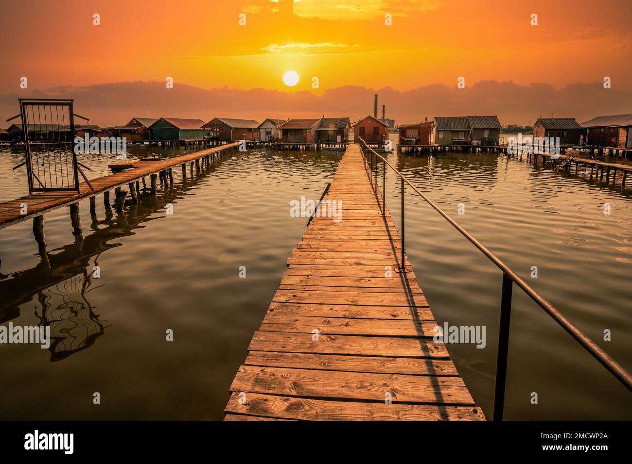 Piccole case di legno con un molo in un lago, servono come case di pesca e vacanze per gli ungheresi. Bellissima foto di paesaggio al tramonto, Lago Bokodi Foto Stock