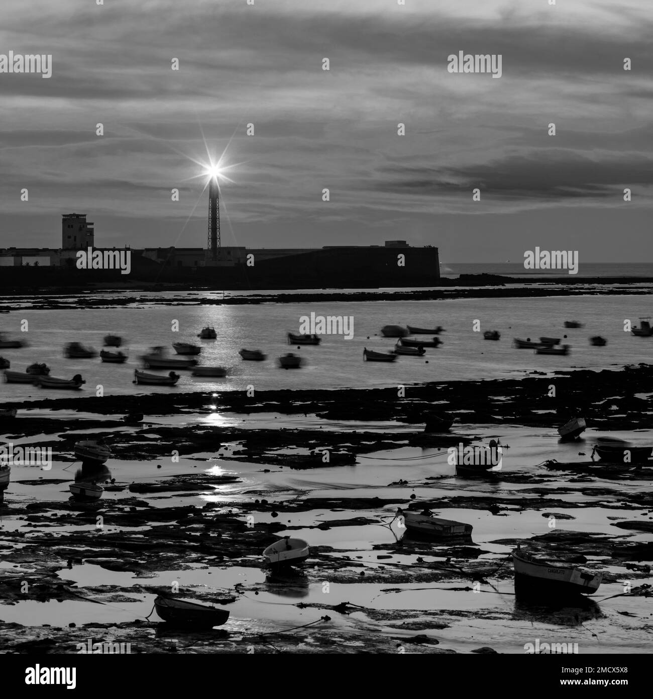 Bianco e nero, faro, Faro del Castillo de San Sebastian, barche da pesca, tramonto, bassa marea, Cadiz città, Costa de la Luz, Cadice, Andalusia Foto Stock