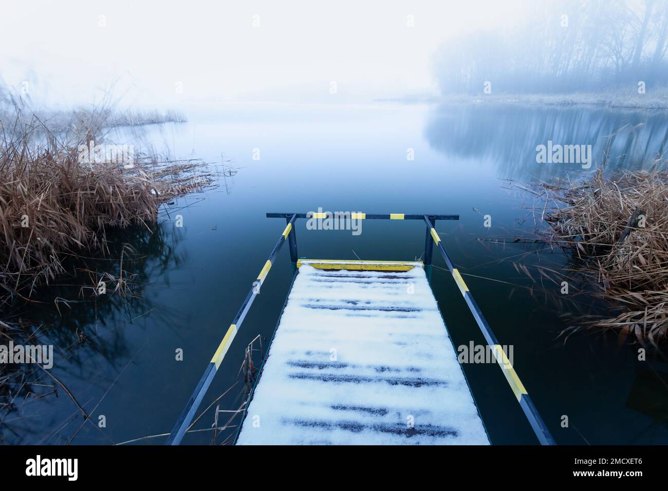 Un molo con corrimano per disabili sulla riva di un lago in una giornata di nebbia, Stankow, Polonia Foto Stock