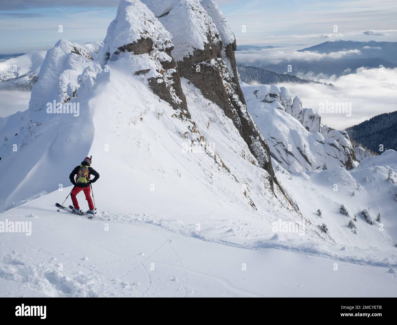 Solitario sciatore free-rider in alta montagna. Sci freestyle estremo nella luce del sole sul paesaggio montano di inverno Foto Stock