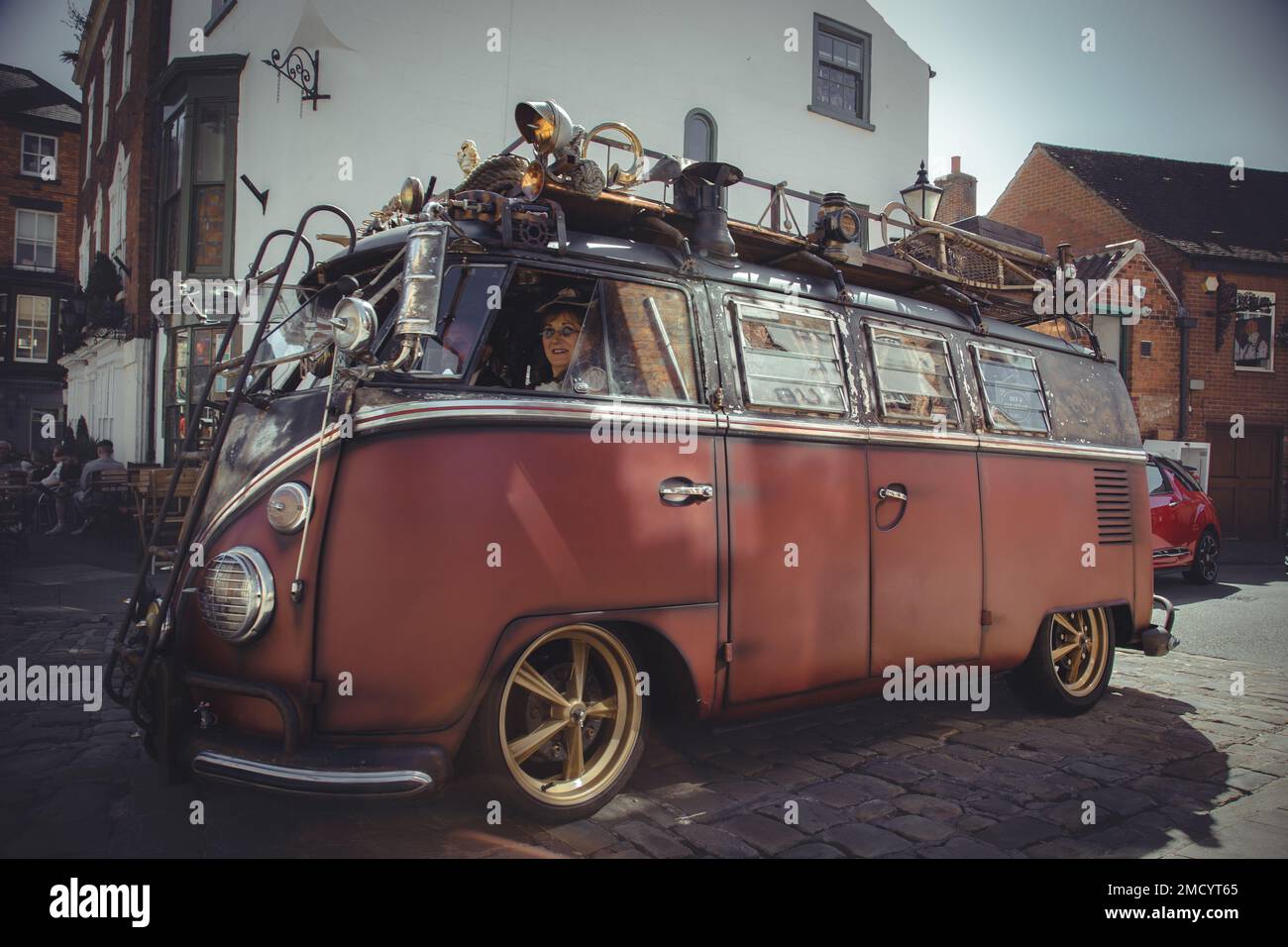 Un camper Volkswagen personalizzato che viaggia su una strada acciottolata. Camper VW personalizzato steampunk. Foto Stock