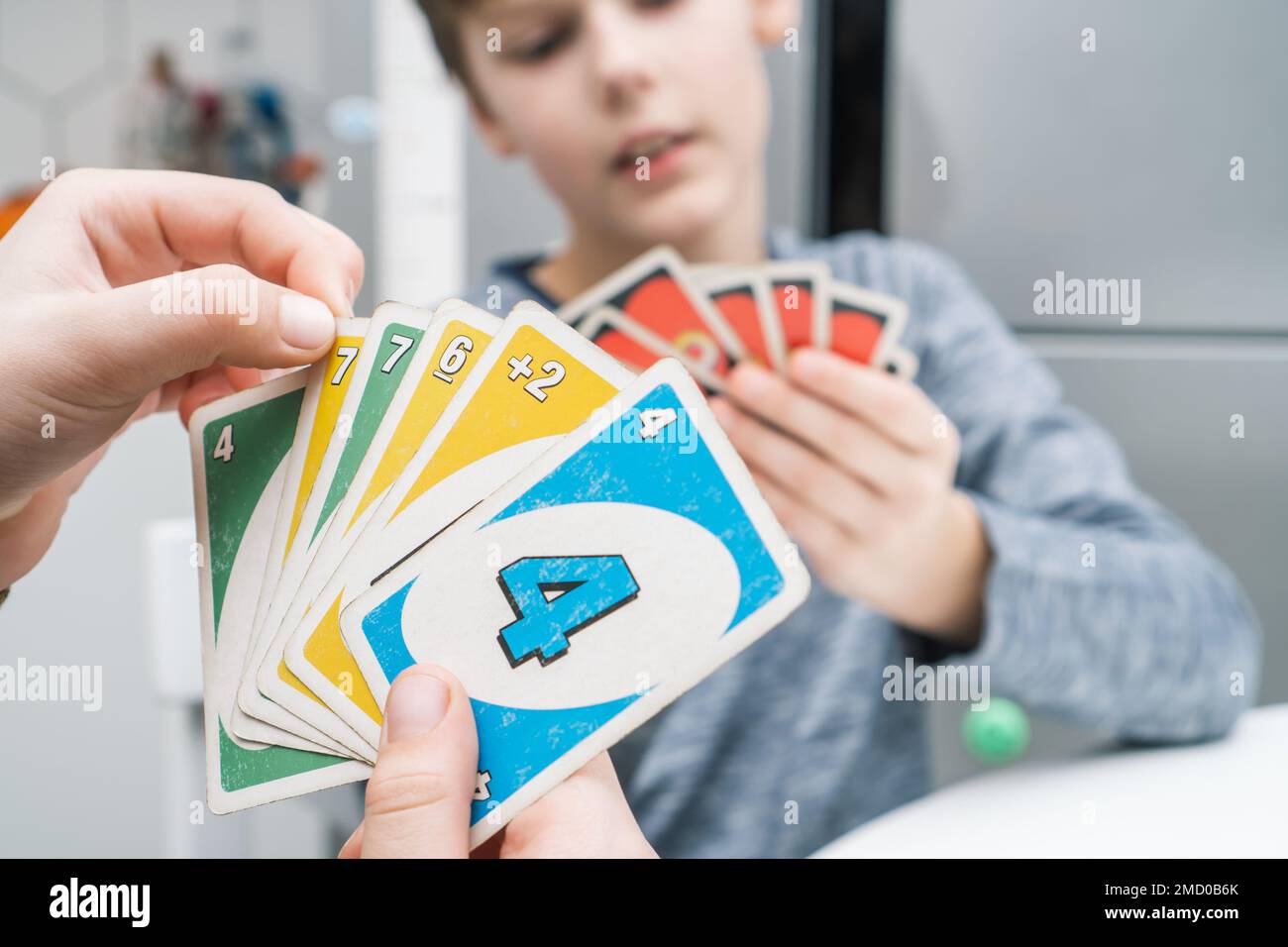 Minsk, Bielorussia 08.01.23 foto ritagliata di due ragazzi amici bambini seduti al tavolo in cucina a casa, tenendo carte di gioco di carte uno, tavolo da gioco Foto Stock