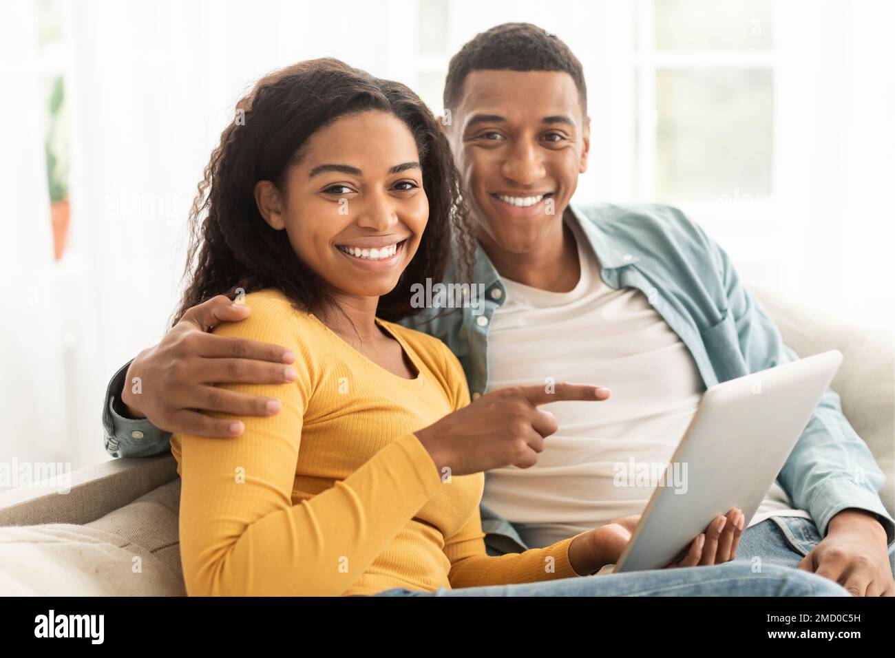 Felice giovane afroamericano ragazzo e signora punto dito al telefono, hanno videochiamata, navigare in internet Foto Stock