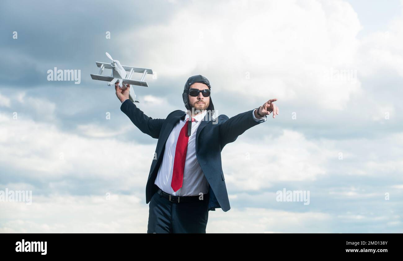 businessperson in tuta e cappello pilota lancio aereo giocattolo su sfondo cielo Foto Stock