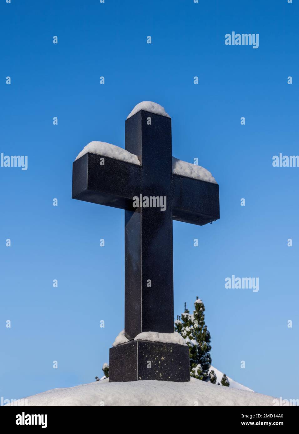 Neve coperto crocifisso storico in un cimitero Foto Stock