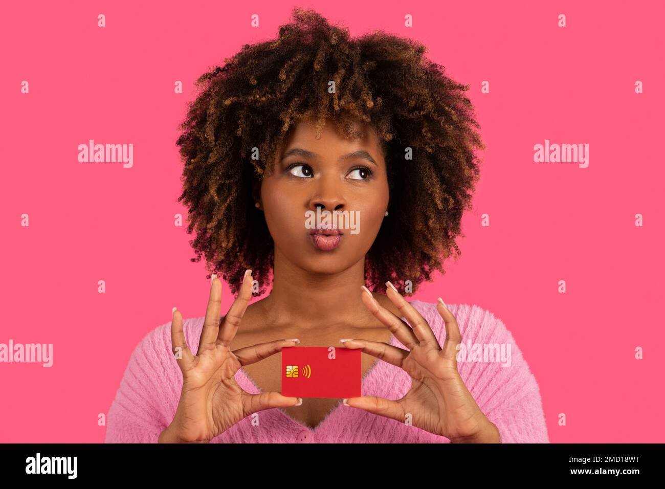 Premuroso giovane afroamericano curly femmina pensando all'acquisto con carta di credito, guardare lo spazio libero Foto Stock