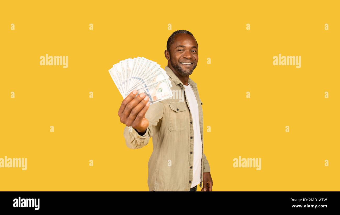 Allegro uomo afro-americano di mezza età in casual show un sacco di soldi in contanti, raccomandare l'investimento Foto Stock