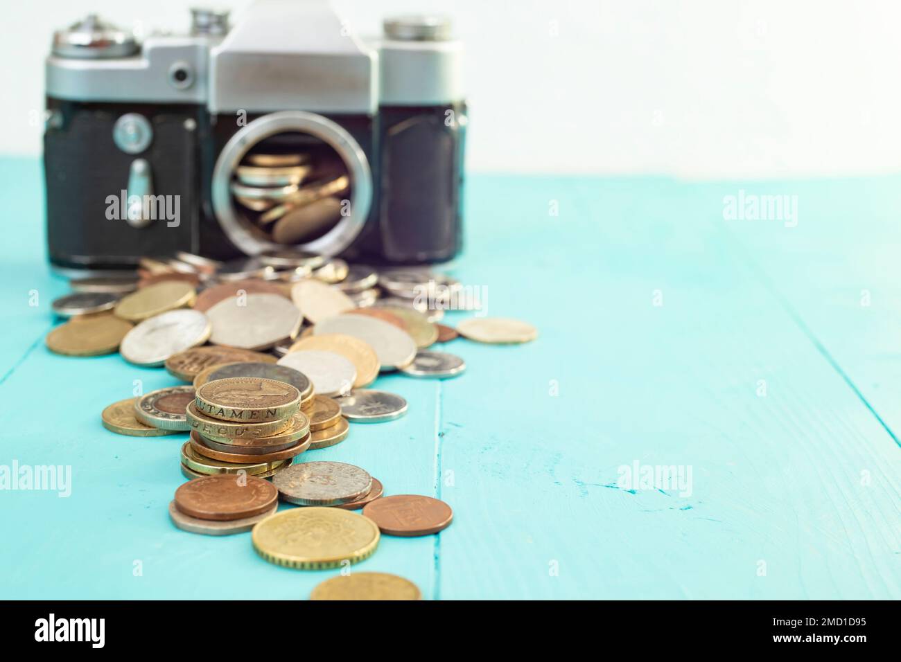 Fotocamera d'epoca sfocata con monete in primo piano, su sfondo blu, primo piano con messa a fuoco morbida Foto Stock